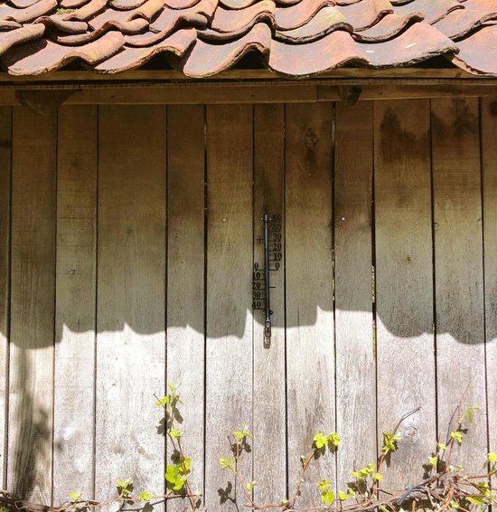 Thermometer aan houten schutting met dakpannen